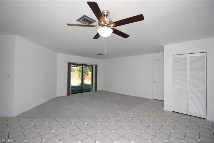 Carpeted empty room featuring ceiling fan