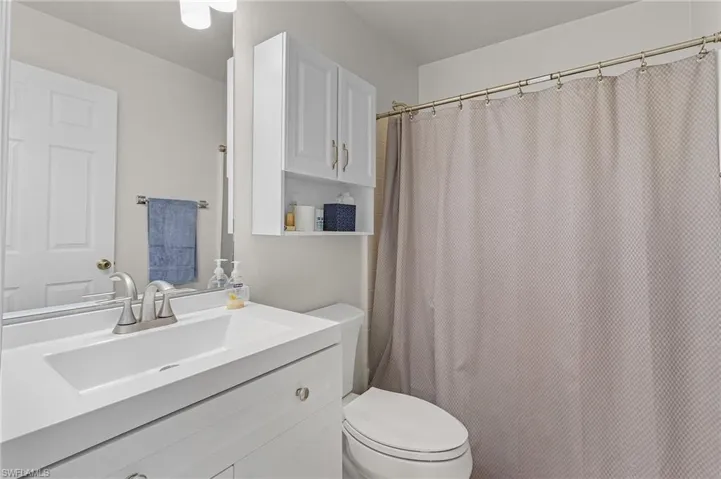 Full bathroom featuring a shower with shower curtain, toilet, and vanity