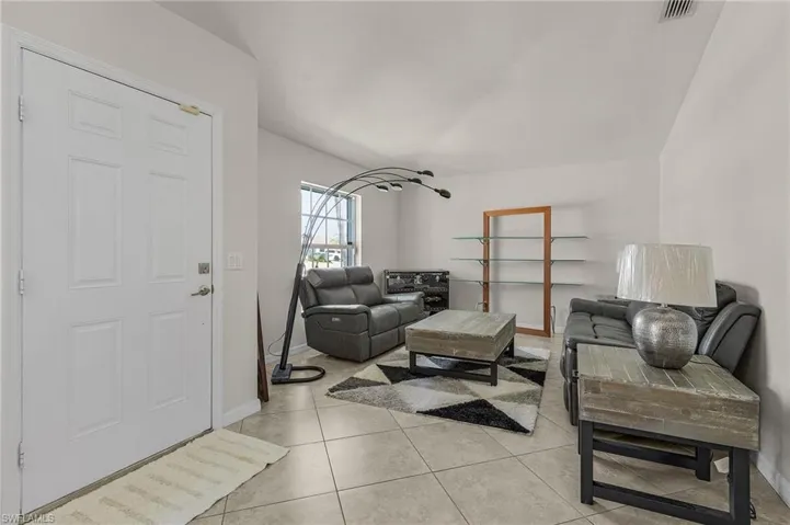 Living room featuring light tile patterned flooring, visible vents, and baseboards