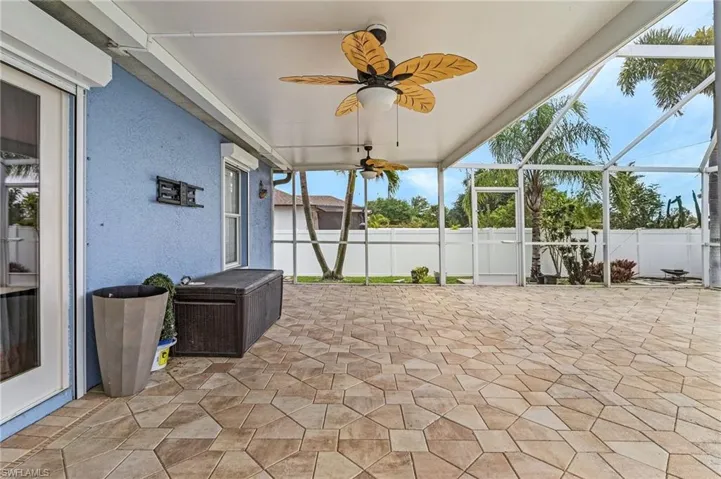 View of patio with fence, a ceiling fan, and glass enclosure