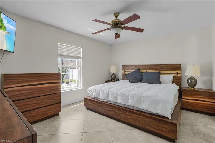 Bedroom with light tile patterned flooring, baseboards, and ceiling fan