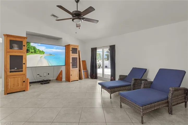 Living area with ceiling fan, lofted ceiling, visible vents, and light tile patterned floors