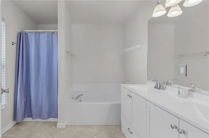Bathroom with a sink, a bath, a shower with curtain, double vanity, and tile patterned flooring