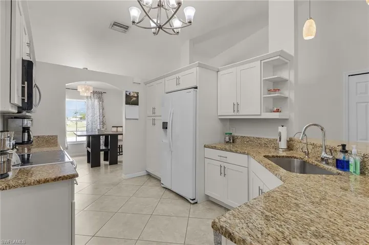 Kitchen with a sink, arched walkways, an inviting chandelier, stainless steel appliances, and visible vents