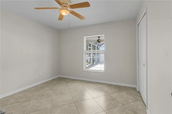 Unfurnished room with light tile patterned flooring, a ceiling fan, and baseboards
