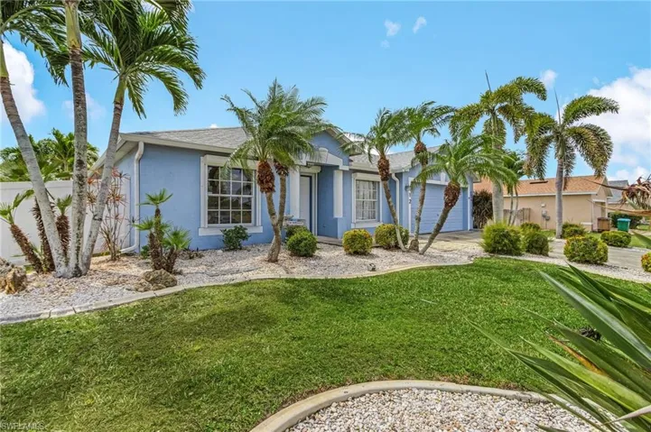 Single story home featuring a garage, driveway, a front lawn, and stucco siding