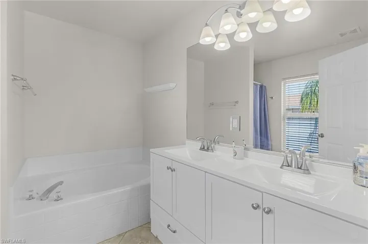 Full bath with double vanity, a bath, tile patterned flooring, and a sink