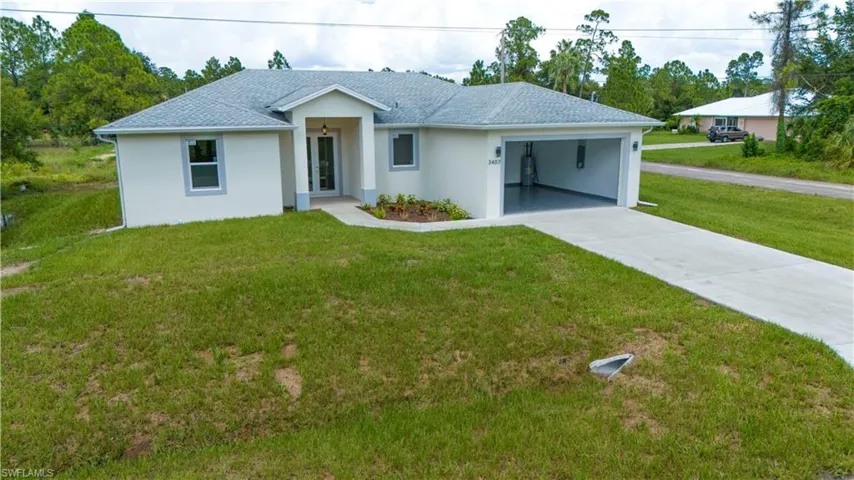 View of front of home with an attached garage, concrete driveway, a front yard, and stucco siding
