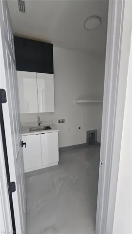 Clothes washing area with hookup for a washing machine, cabinets, and sink
