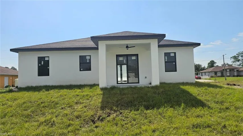 Rear view of property featuring ceiling fan and a lawn