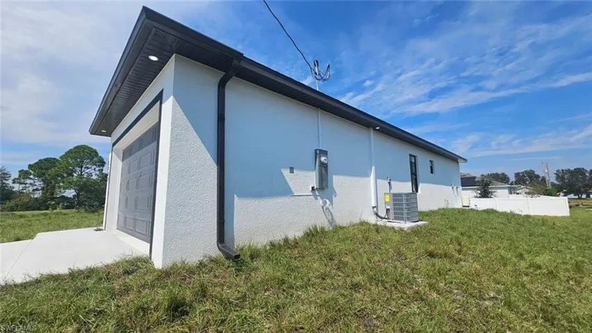 View of side of home featuring a yard, a garage, and central AC unit