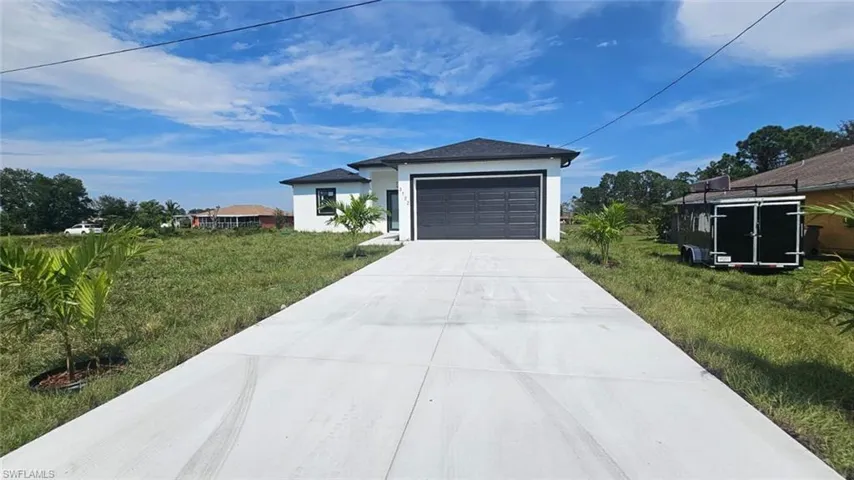 View of front of property featuring a garage and a front lawn