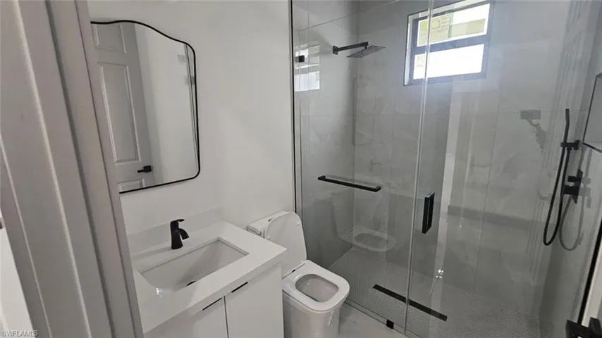 Bathroom featuring vanity, toilet, and a shower with shower door