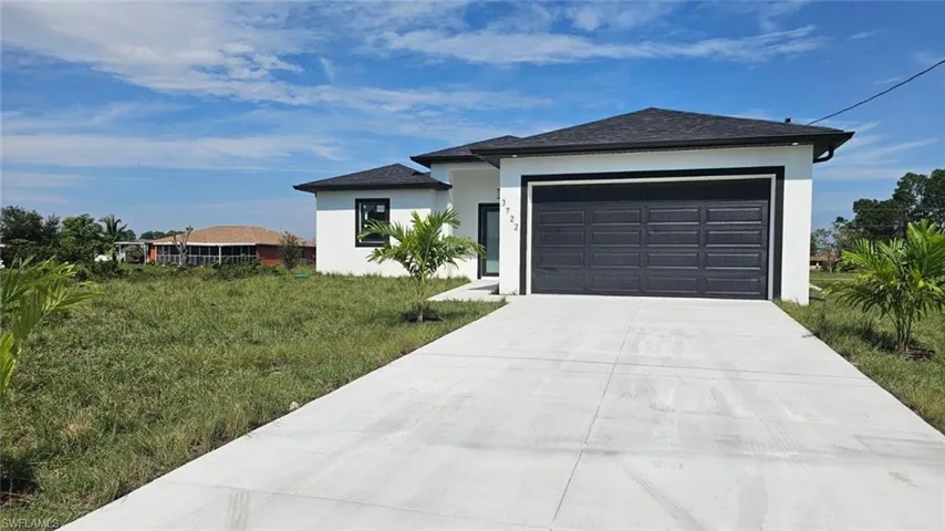 View of front facade featuring a front yard and a garage