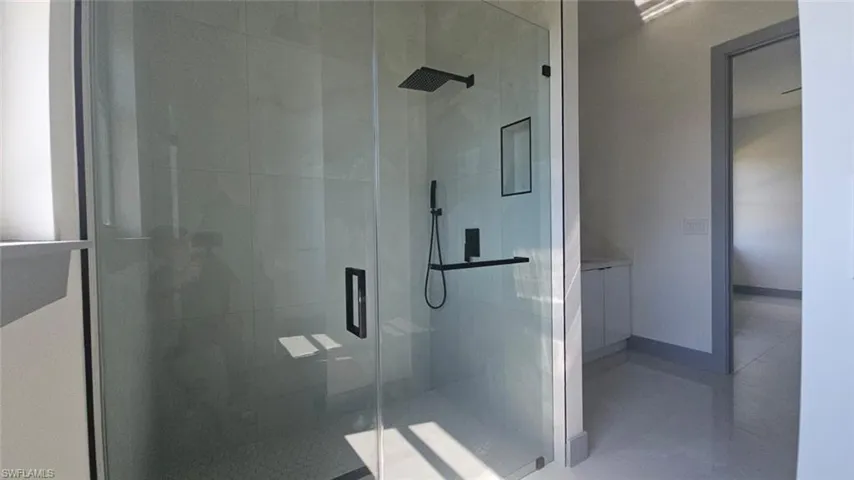 Bathroom with a shower with shower door and tile patterned flooring