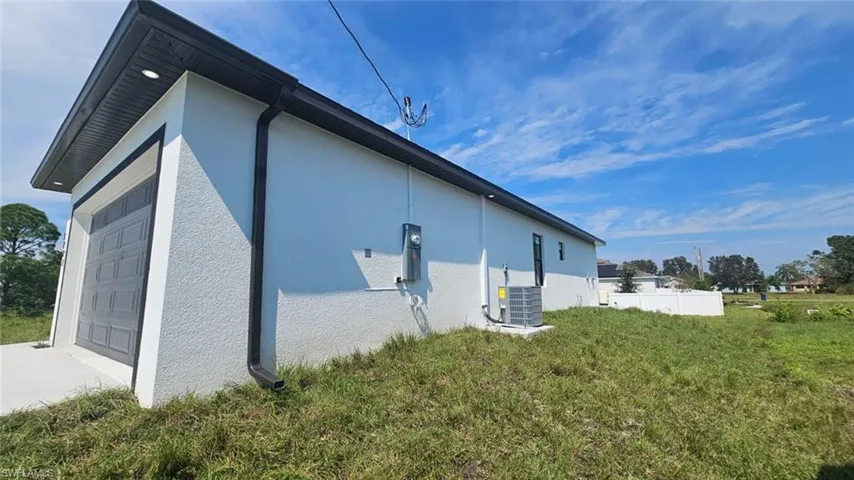 View of property exterior with a lawn, cooling unit, and a garage