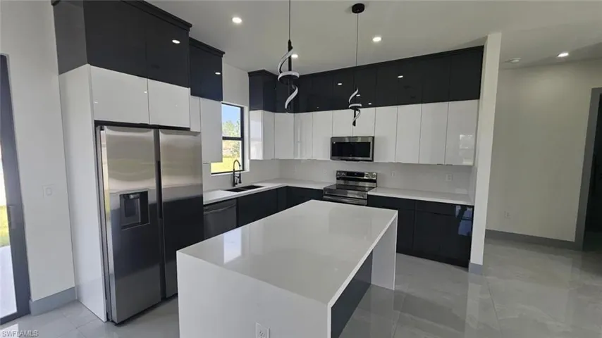 Kitchen featuring appliances with stainless steel finishes, sink, a kitchen island, pendant lighting, and white cabinets