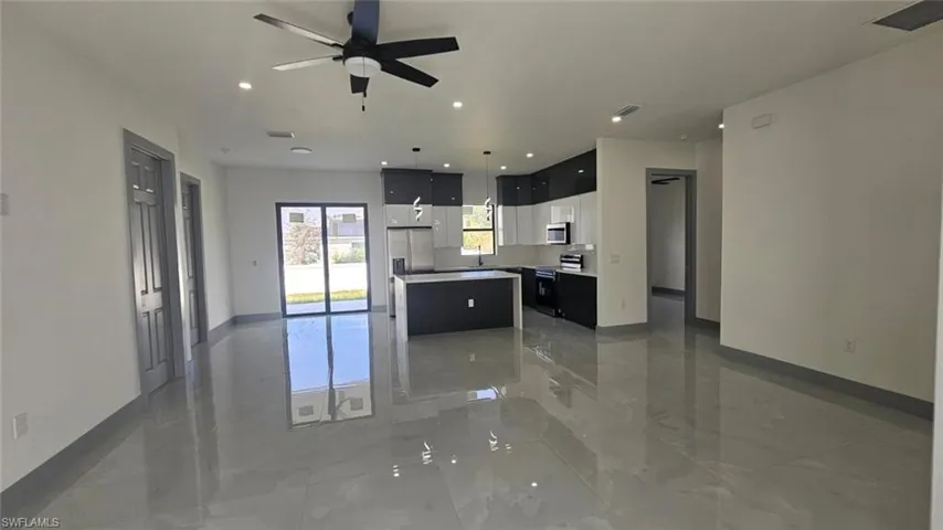 Kitchen featuring sink, a center island, decorative light fixtures, appliances with stainless steel finishes, and ceiling fan