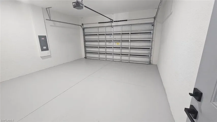 Garage featuring a garage door opener and electric panel