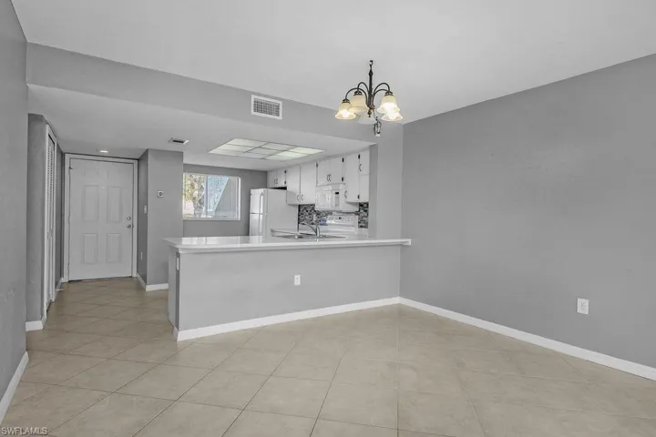 Kitchen featuring light countertops, a chandelier, a peninsula, tasteful backsplash, and white appliances