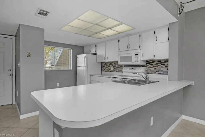 Kitchen featuring a peninsula, light tile patterned flooring, and light countertops