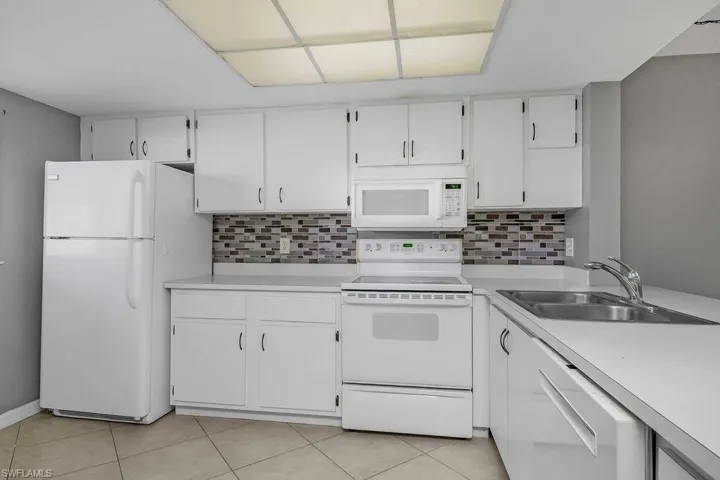 Kitchen with white appliances, white cabinets, and light countertops