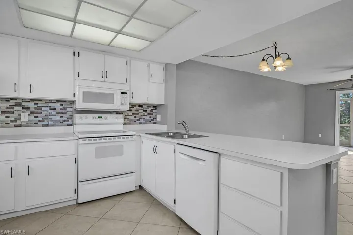 Kitchen with white appliances, white cabinets, light countertops, and light tile patterned floors