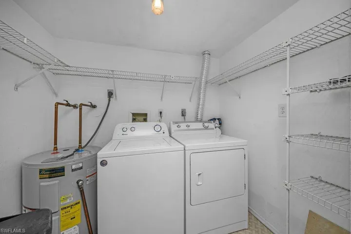 Laundry room with electric water heater and washer and clothes dryer