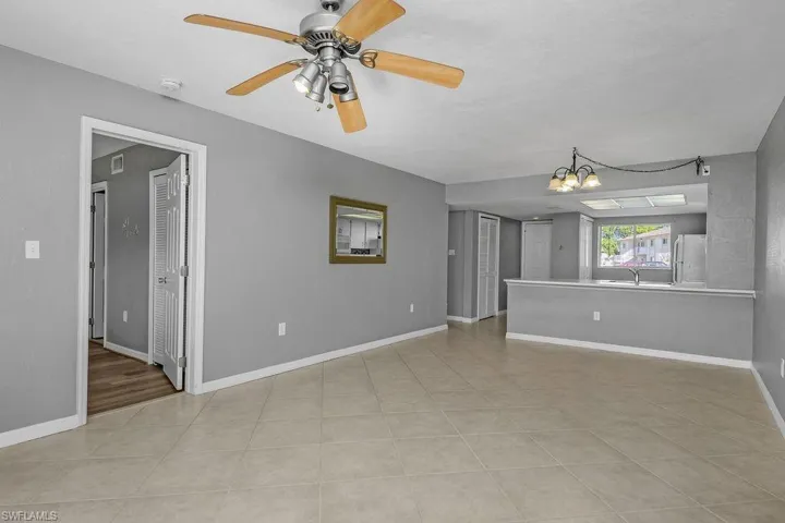 Unfurnished living room with a chandelier, a ceiling fan, and light tile patterned floors