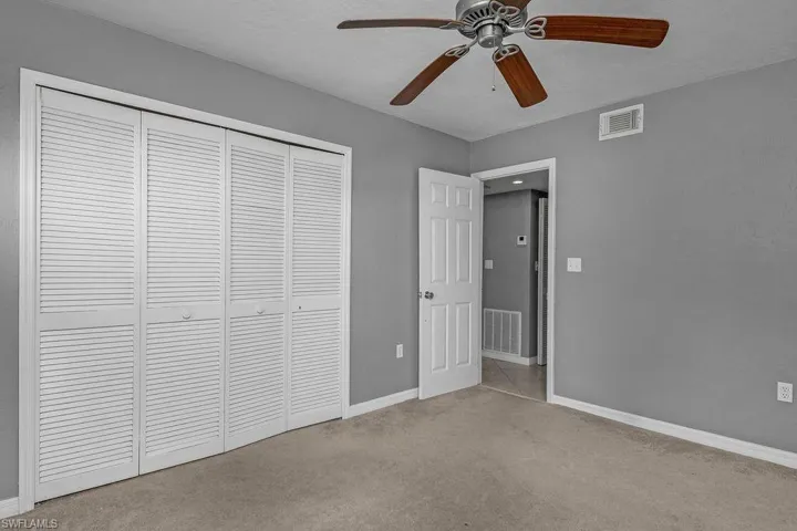 Unfurnished bedroom featuring light colored carpet, ceiling fan, and a closet