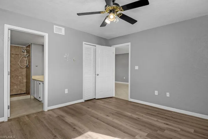 Unfurnished bedroom with light wood finished floors, a ceiling fan, and connected bathroom