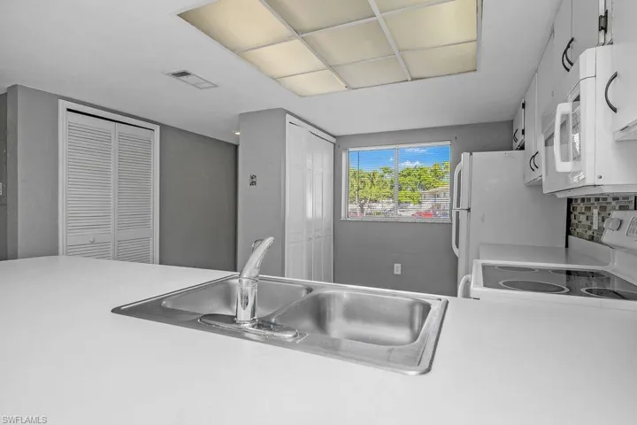 Kitchen featuring light countertops, white cabinetry, and white appliances