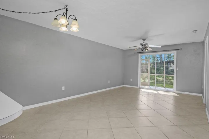 Empty room featuring a chandelier, light tile patterned floors, and ceiling fan