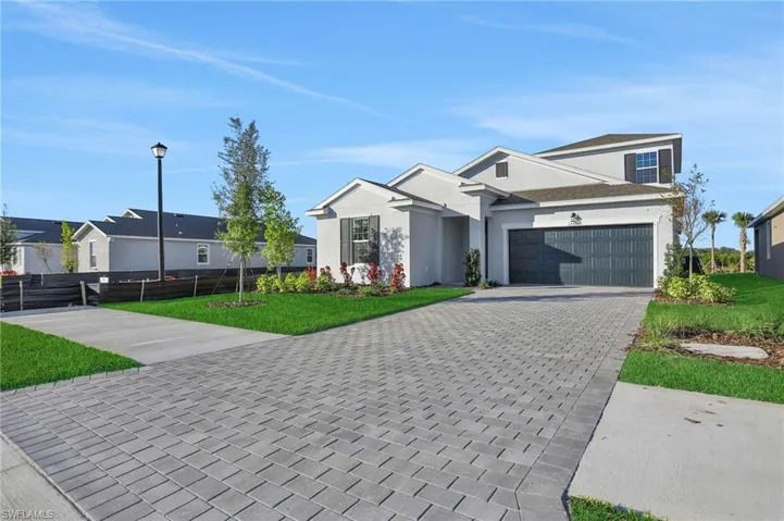 View of front facade with driveway, stucco siding, and a garage