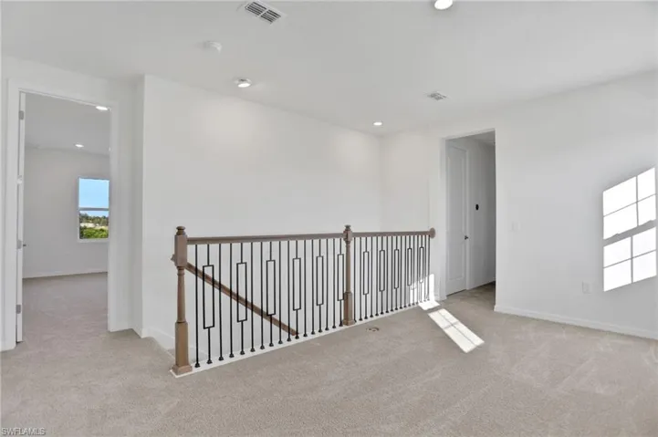 Hallway with an upstairs landing, light colored carpet, and recessed lighting