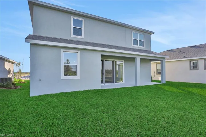 Rear view of house with a lawn, stucco siding, and a patio