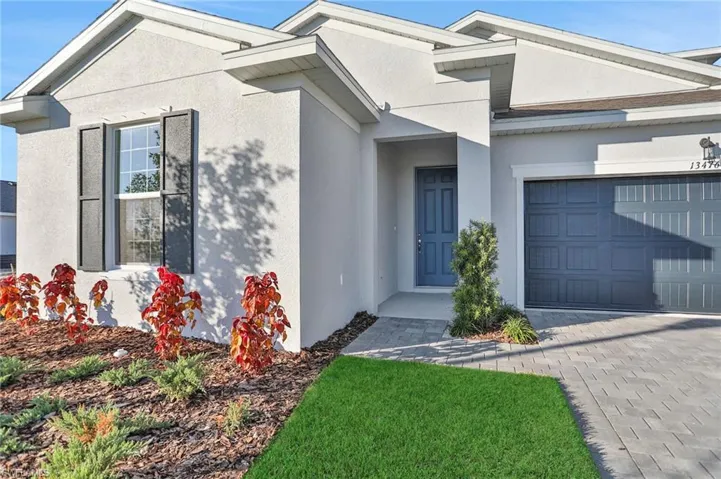 View of front of house with stucco siding, decorative driveway, and a garage