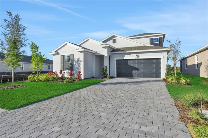 View of front of house featuring a front lawn, driveway, stucco siding, and an attached garage