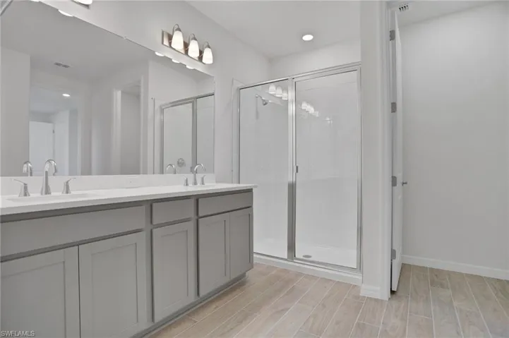 Full bath with wood tiled floors, a stall shower, double vanity, and recessed lighting