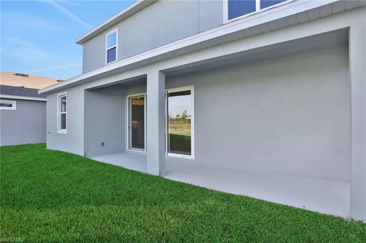 Back of house with stucco siding, a patio area, and a yard