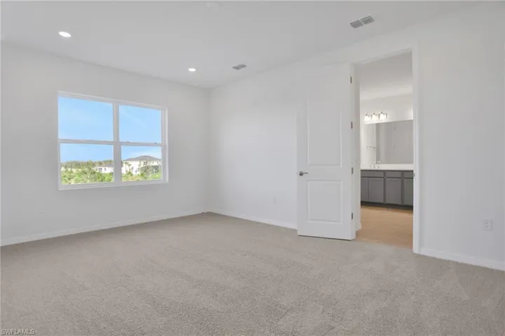Unfurnished bedroom with light colored carpet, recessed lighting, and connected bathroom