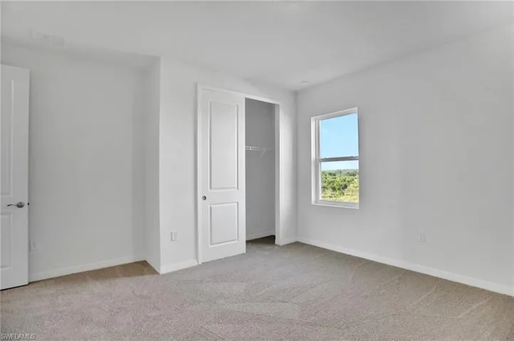 Unfurnished bedroom with light carpet and a closet