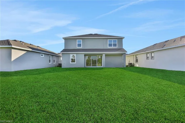 Back of house featuring stucco siding and a lawn