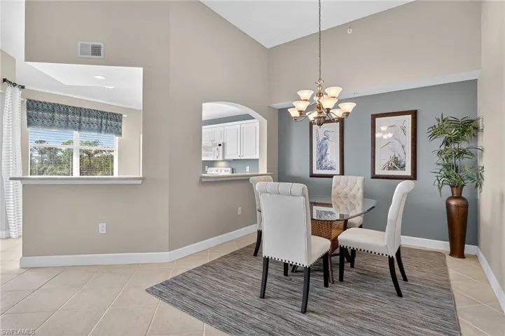 Dining space with light tile patterned floors, a chandelier, high vaulted ceiling, and arched walkways