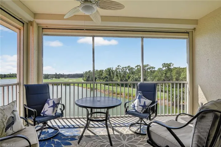 Sunroom / solarium featuring view of wooded area, golf course and a water view