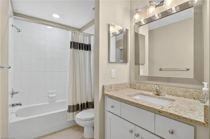 Bathroom featuring shower / bathtub combination with curtain, vanity, and light tile patterned floors