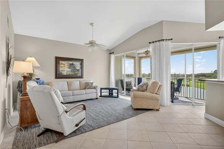 Living area with vaulted ceiling, light tile patterned floors, and ceiling fan