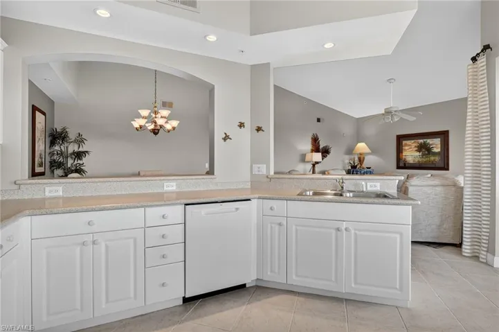 Kitchen with white cabinets, dishwasher, vaulted ceiling, recessed lighting, and light tile patterned flooring