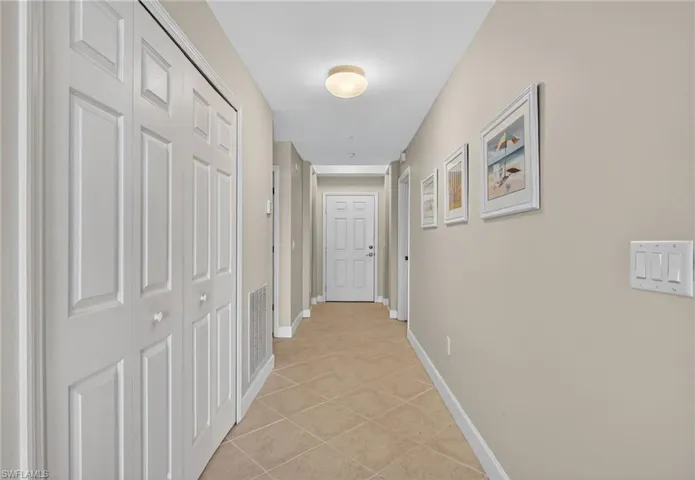 Hallway with light tile patterned flooring and baseboards