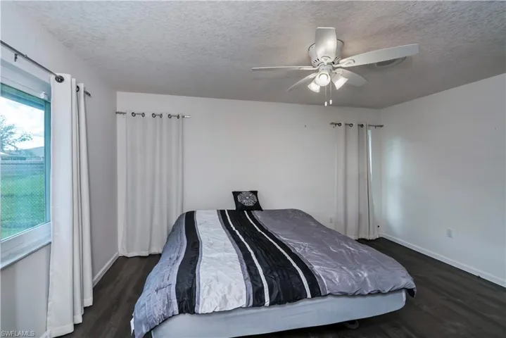 Bedroom featuring a textured ceiling, dark wood-type flooring, and ceiling fan